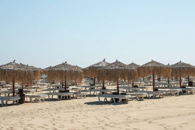 Photo of Beautiful straw umbrellas and sunbeds on sandy beach