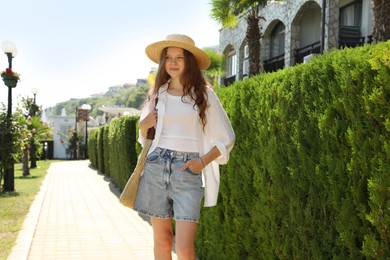 Photo of Beautiful girl in straw hat near hotel outdoors on sunny day