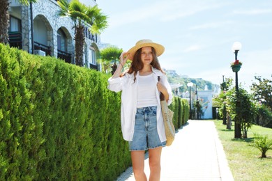 Photo of Beautiful girl in straw hat near hotel outdoors on sunny day