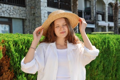 Photo of Beautiful girl in straw hat near hotel outdoors on sunny day