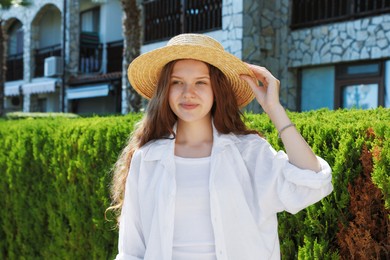 Photo of Beautiful girl in straw hat near hotel outdoors on sunny day