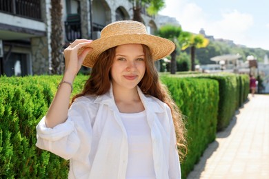 Photo of Beautiful girl in straw hat near hotel outdoors on sunny day