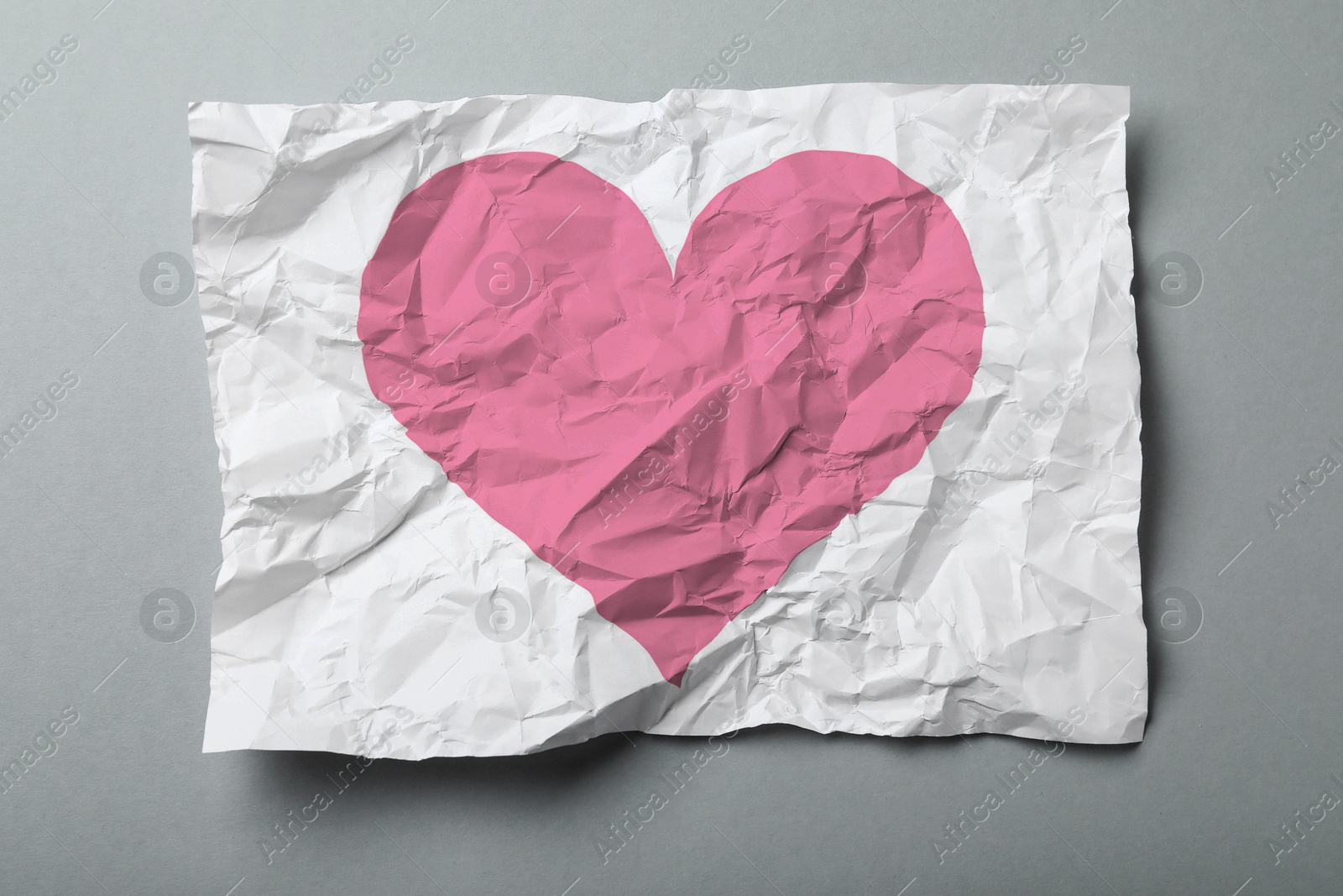 Image of Betrayal. Crumpled sheet of paper with pink heart on grey background, top view