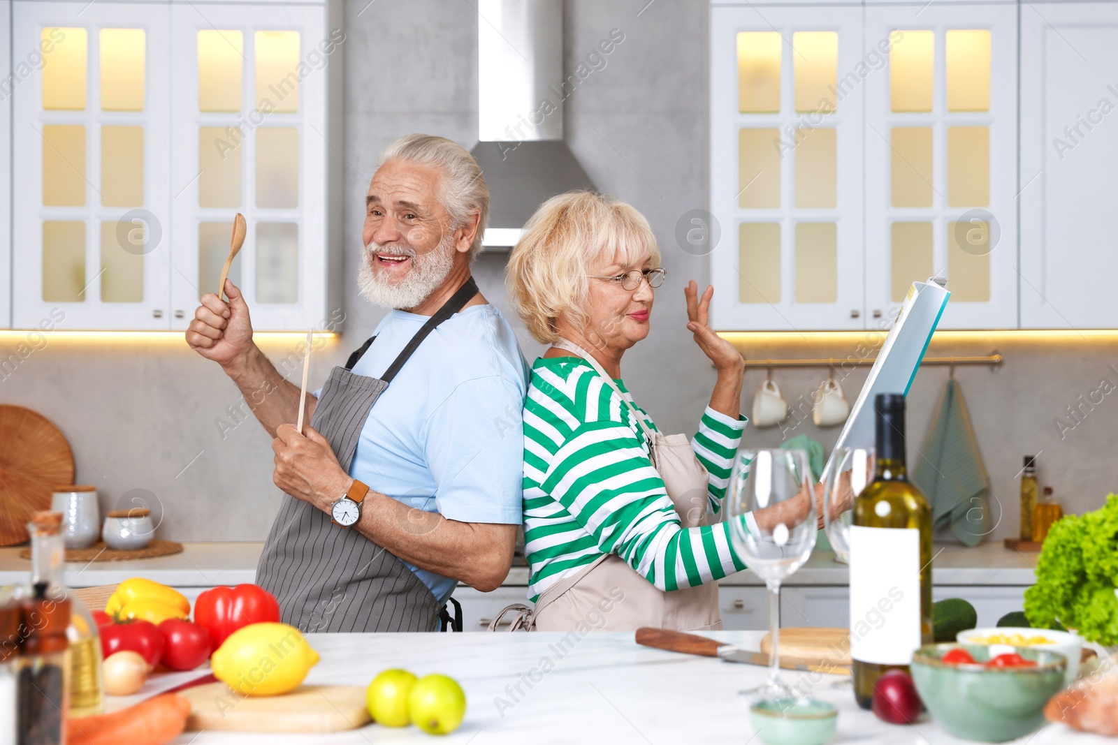 Elderly couple having fun while cooking together at table in kitchen Photo of Elderly couple having fun while cooking together at table in kitchen