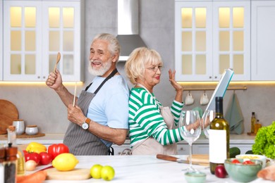 Photo of Elderly couple having fun while cooking together at table in kitchen