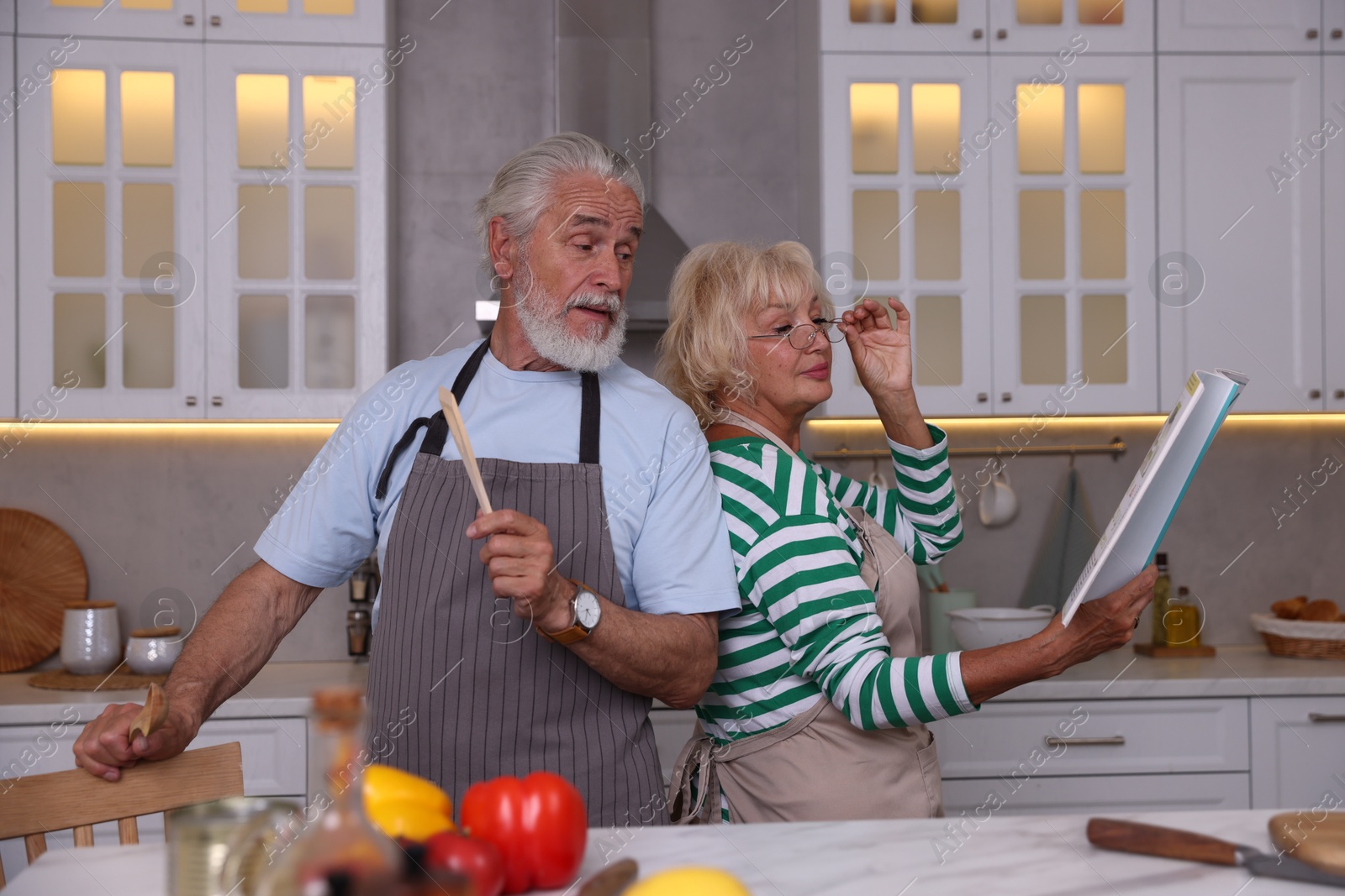 Elderly couple having fun while cooking together at table in kitchen Photo of Elderly couple having fun while cooking together at table in kitchen