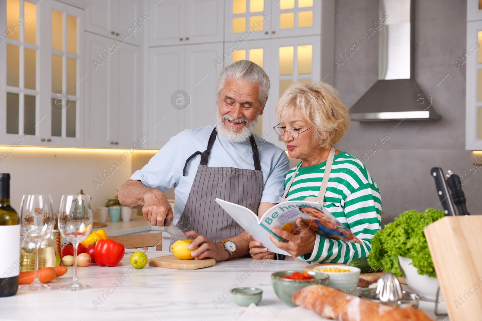 Elderly couple cooking together at marble table in kitchen Photo of Elderly couple cooking together at marble table in kitchen