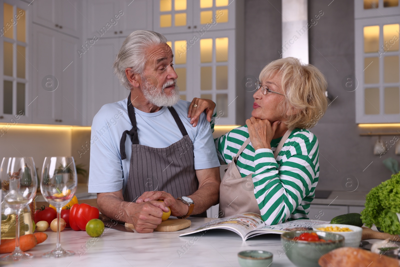 Elderly couple cooking together at marble table in kitchen Photo of Elderly couple cooking together at marble table in kitchen
