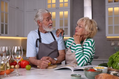 Photo of Elderly couple cooking together at marble table in kitchen