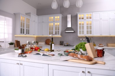 Photo of Different products and bottle of wine on counter in stylish kitchen
