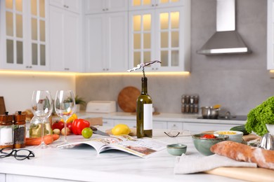 Photo of Different products and bottle of wine on counter in stylish kitchen