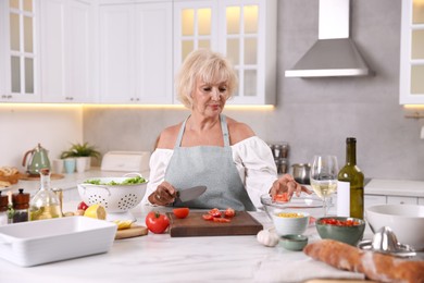 Photo of Senior woman cooking at table in kitchen