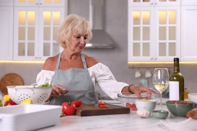 Photo of Senior woman cooking at table in kitchen