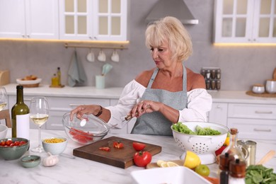 Photo of Senior woman cooking at table in kitchen