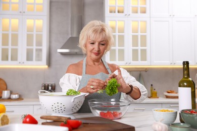 Photo of Senior woman cooking at table in kitchen