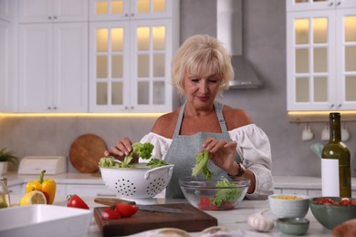 Photo of Senior woman cooking at table in kitchen