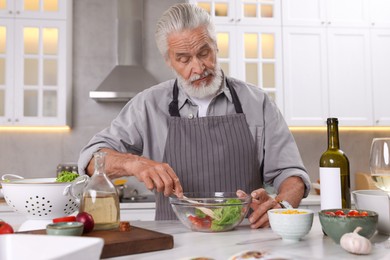 Photo of Elderly man cooking at table in kitchen