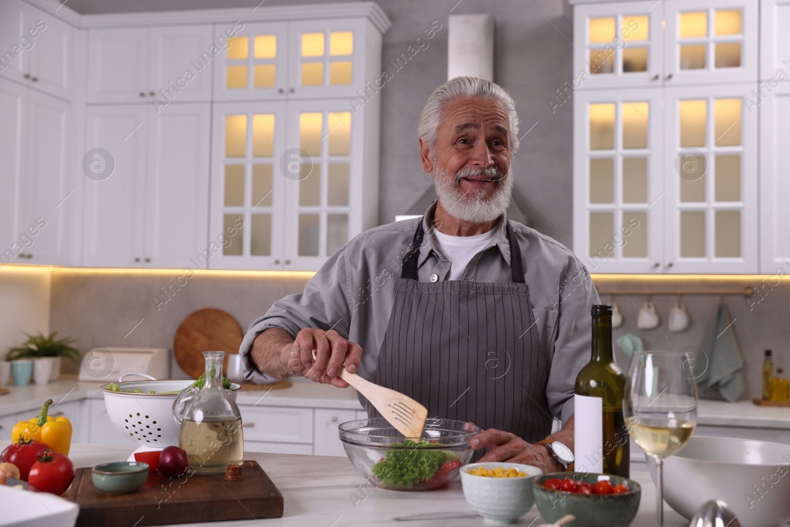 Elderly man cooking at table in kitchen Photo of Elderly man cooking at table in kitchen