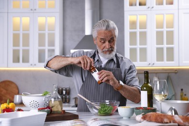 Photo of Elderly man cooking at table in kitchen