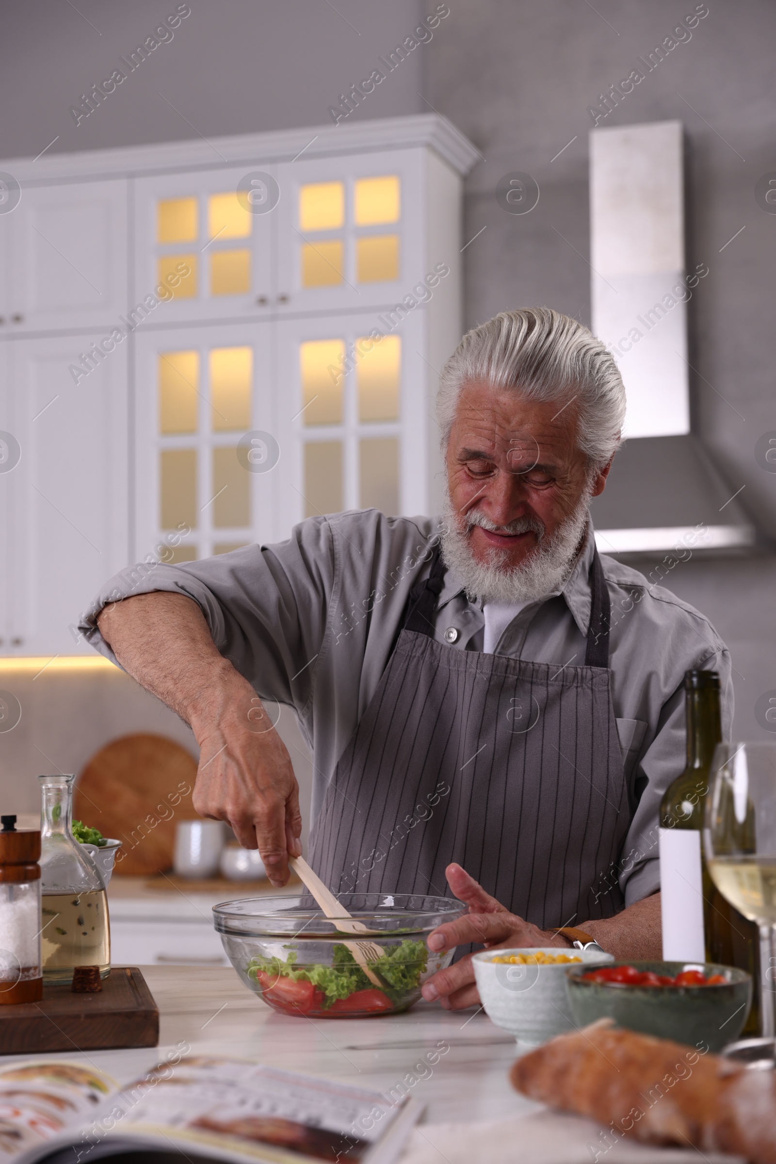 Elderly man cooking at table in kitchen Photo of Elderly man cooking at table in kitchen