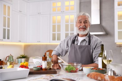 Photo of Elderly man cooking at table in kitchen