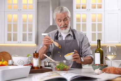 Photo of Elderly man cooking at table in kitchen