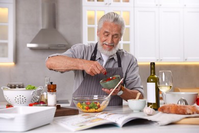 Photo of Elderly man cooking at table in kitchen