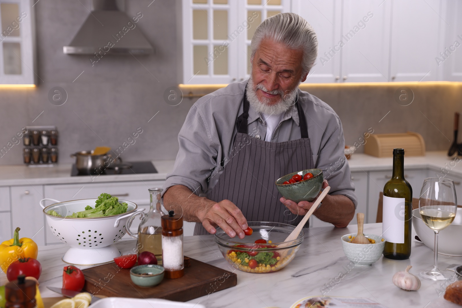 Elderly man cooking at table in kitchen Photo of Elderly man cooking at table in kitchen