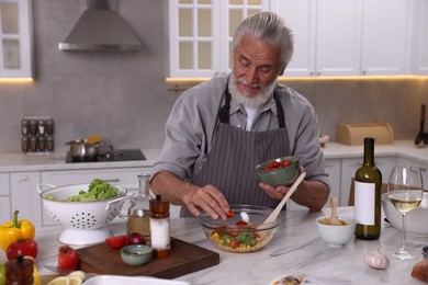 Photo of Elderly man cooking at table in kitchen