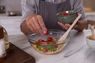 Photo of Elderly man cooking at marble table indoors, closeup