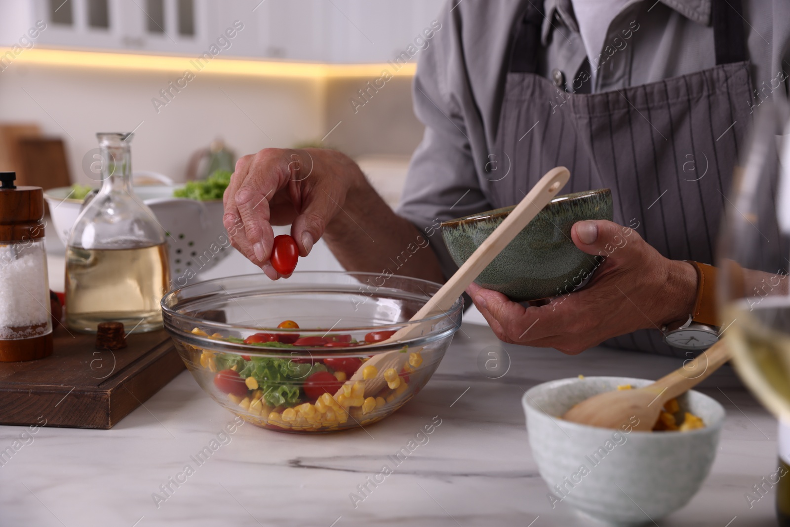 Elderly man cooking at marble table indoors, closeup Photo of Elderly man cooking at marble table indoors, closeup