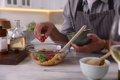 Photo of Elderly man cooking at marble table indoors, closeup