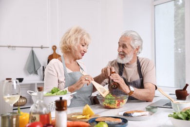 Photo of Elderly couple cooking together at table indoors
