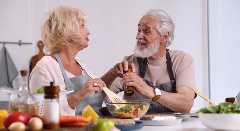 Photo of Elderly couple cooking together at table indoors