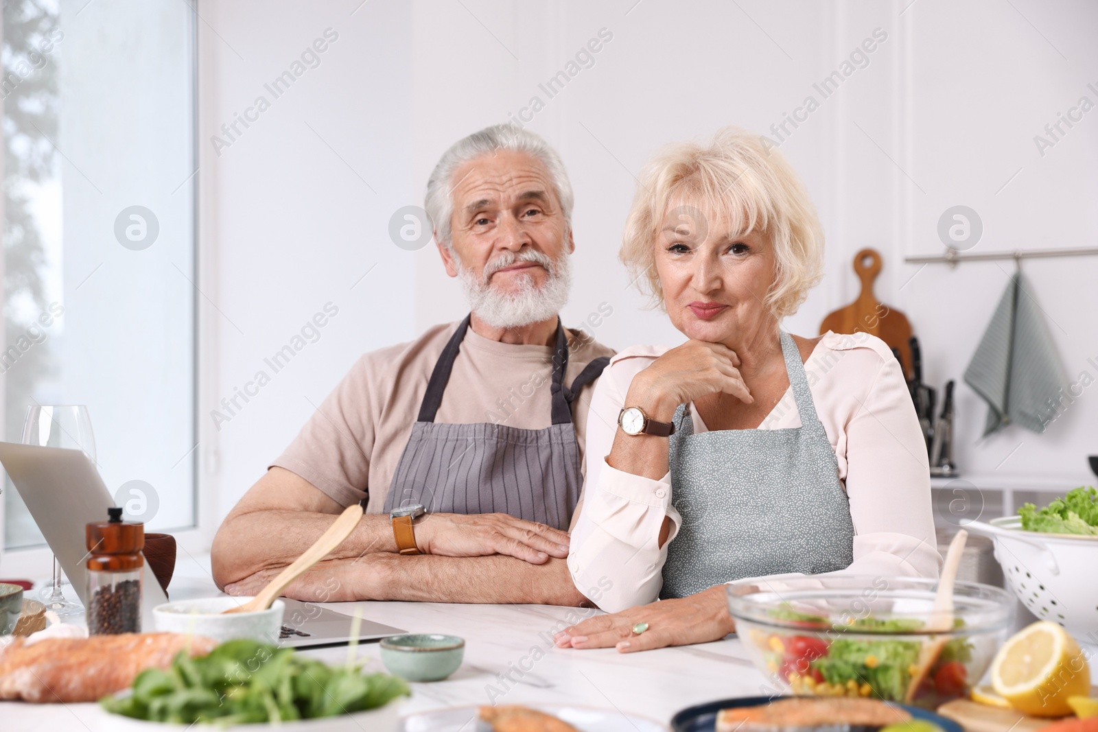 Portrait of elderly couple after cooking together at table indoors Photo of Portrait of elderly couple after cooking together at table indoors