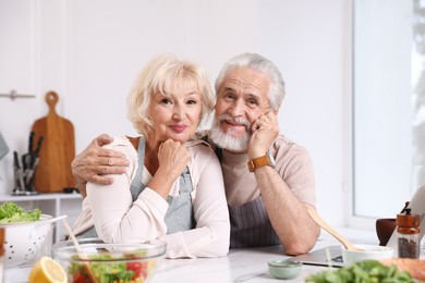Photo of Portrait of elderly couple after cooking together at table indoors