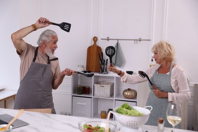 Photo of Elderly couple having fun while cooking together in kitchen