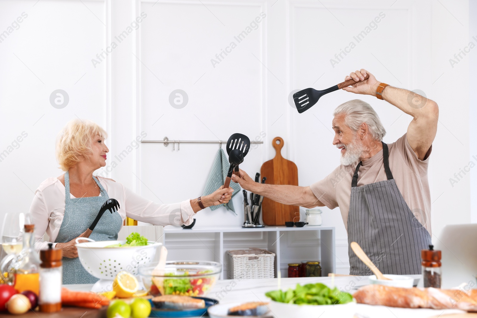 Elderly couple having fun while cooking together in kitchen Photo of Elderly couple having fun while cooking together in kitchen