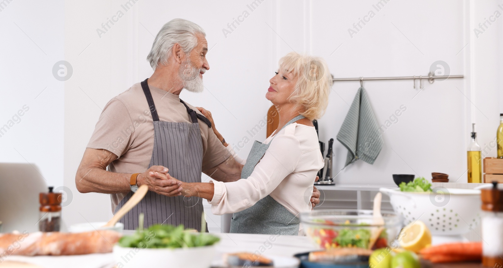 Elderly couple dancing after cooking together in kitchen Photo of Elderly couple dancing after cooking together in kitchen