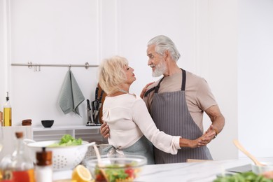 Photo of Elderly couple dancing after cooking together in kitchen