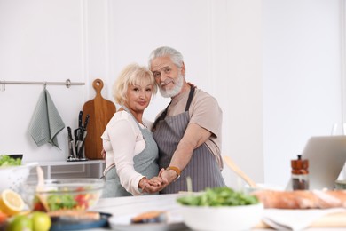 Photo of Elderly couple dancing after cooking together in kitchen