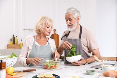 Photo of Elderly couple cooking together at table in kitchen