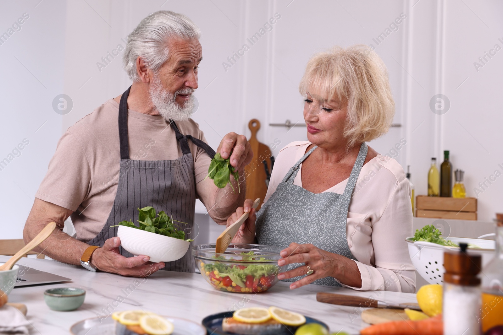 Elderly couple cooking together at table in kitchen Photo of Elderly couple cooking together at table in kitchen