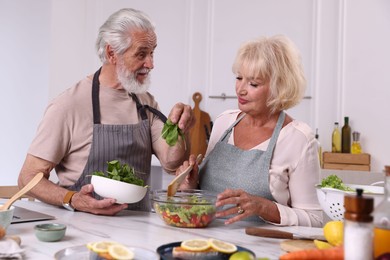 Photo of Elderly couple cooking together at table in kitchen