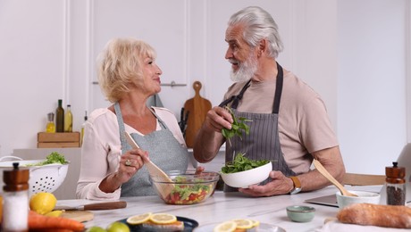 Photo of Elderly couple cooking together at table in kitchen