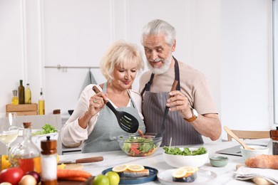 Photo of Elderly couple cooking together at table in kitchen