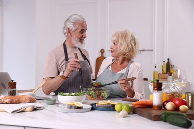 Photo of Elderly couple cooking together at table in kitchen