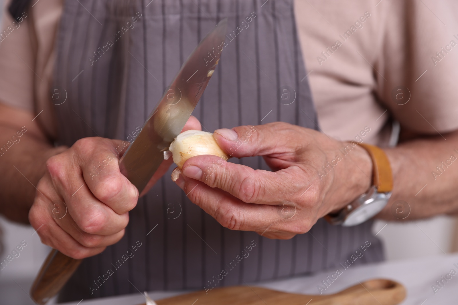 Elderly man with onion and knife indoors, closeup Photo of Elderly man with onion and knife indoors, closeup