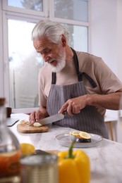 Photo of Elderly man cooking at marble table indoors