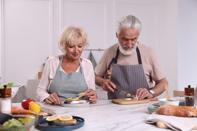 Photo of Elderly couple cooking together at marble table in kitchen